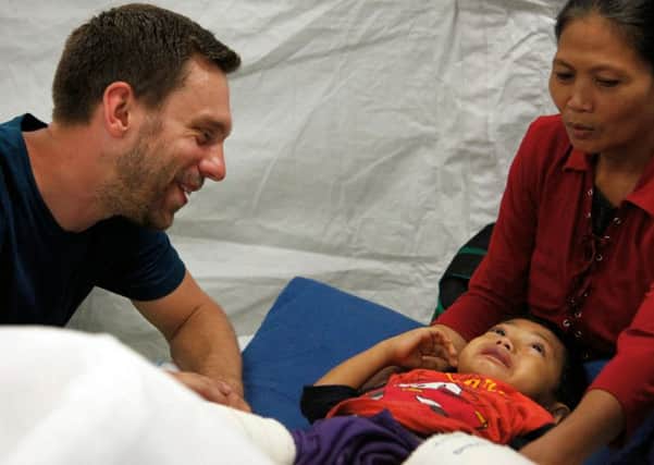 Pete Skelton, seen here helping a little boy in the Philippines,  is part of the UK Emergency Medical Team.