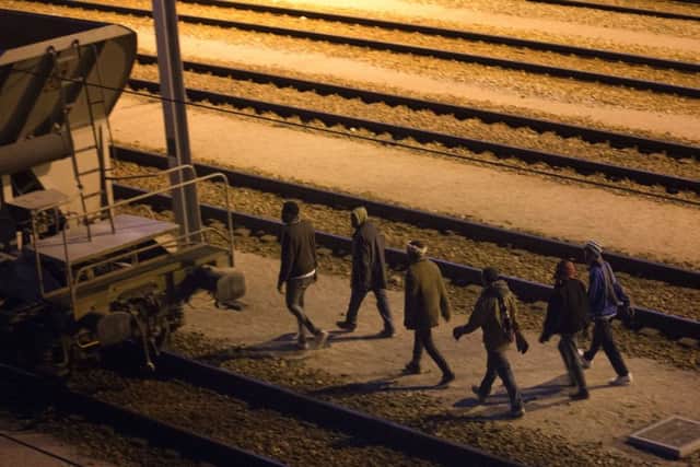 Migrants walk along the train tracks after crossing a fence as they attempt to access the Channel Tunnel in Calais, Friday, Aug. 7, 2015. An estimated 2,500 migrants are currently at the windswept camp surrounded by sand dunes that sprung up when a state-approved day center for migrants was opened nearby. The ramshackle encampment of tents and lean-tos is referred to as the "jungle," like the camps it replaced. (AP Photo/Emilio Morenatti)