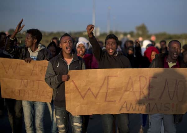 Migrants march toward the Channel Tunnel during a demonstration in Calais, northern France, Friday, Aug. 7, 2015. An estimated 2,500 migrants are currently at the windswept camp surrounded by sand dunes that sprung up when a state-approved day center for migrants was opened nearby. The ramshackle encampment of tents and lean-tos is referred to as the "jungle," like the camps it replaced. (AP Photo/Emilio Morenatti)