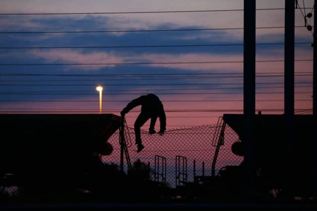 A migrant climbing over a fence on to the tracks near the Eurotunnel site at Coquelles in Calais