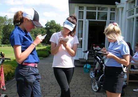 A group of competitors carefully check their cards during the Northern Girls' championship at Headingley GC.