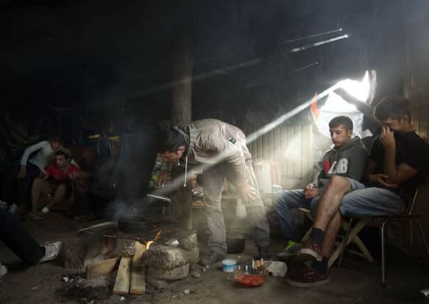 Afghan migrants stay inside a tent as they cook food at a camp set near Calais