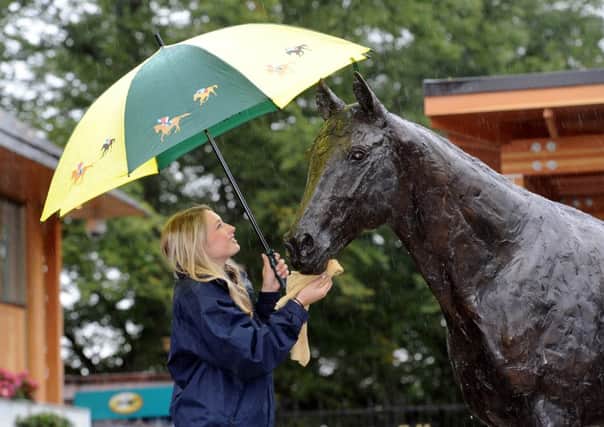 Sophie Blades, from York Racecourse wiping the rain drops off the new Frankel statue.