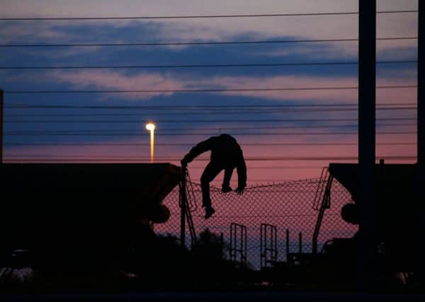 Image of a migrant climbing over a fence on to the tracks near the Eurotunnel site at Coquelles in Calais, France, as British police will be deployed to Calais to target trafficking gangs as part of a fresh drive to tackle the migrant crisis. (Picture: Yui Mok/PA Wire)