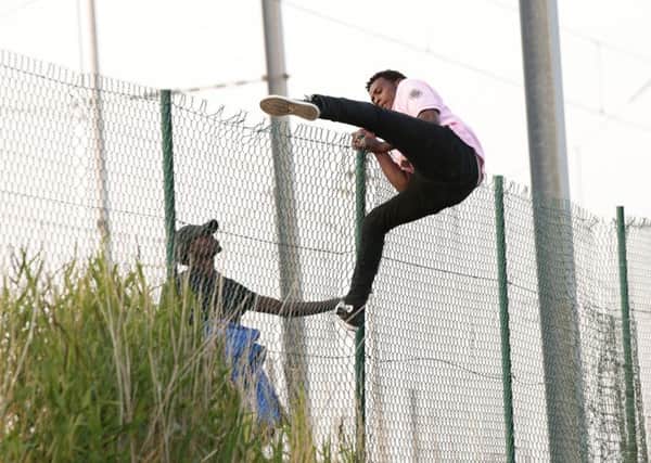 Image of migrants climbing over a fence on to the tracks near the Eurotunnel site at Coquelles in Calais, France, as the number of migrants reaching EU borders has hit a record high, surpassing 100,000 in July. (Picture: Yui Mok/PA Wire)