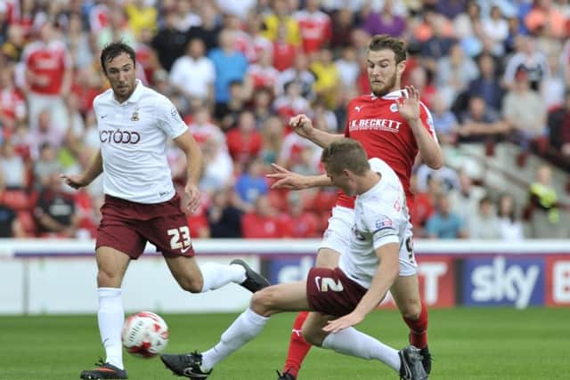 NO WAY THROUGH: Bradford City captain Stephen Darby clears the danger as Barnsley striker Sam Winnall rushes in at Oakwell. Pictures: Dean Atkins.