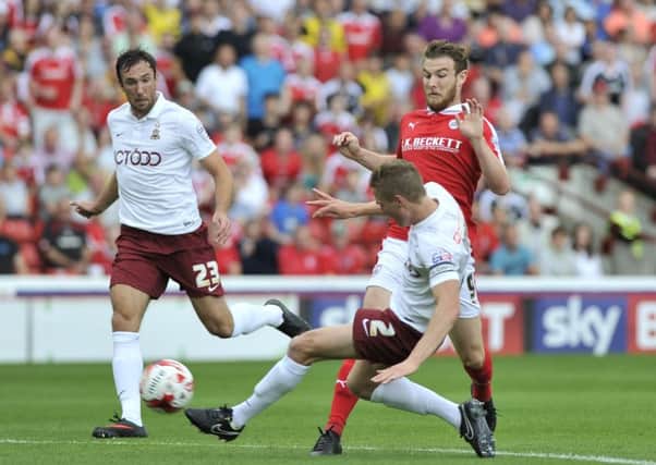 NO WAY THROUGH: Bradford City captain Stephen Darby clears the danger as Barnsley striker Sam Winnall rushes in at Oakwell. Pictures: Dean Atkins.