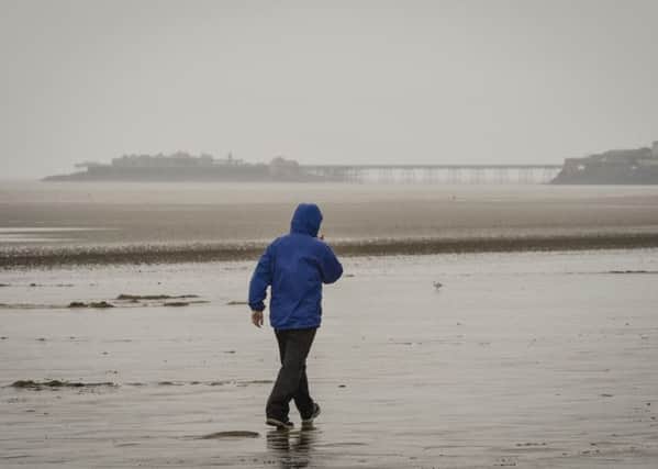 A person braves the deserted and wet beach at Weston-super-Mare, Somerset, where rain continues to fall on a grey and wet day.  PRESS ASSOCIATION Photo. Picture date: Monday August, 24, 2015. Photo credit should read: Ben Birchall/PA Wire