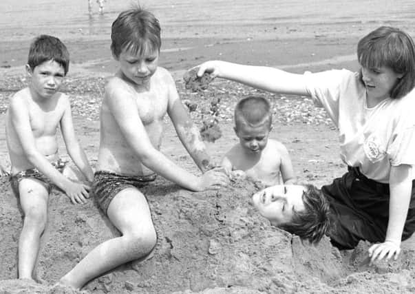 A family has fun burying one another in the sand in 1988.