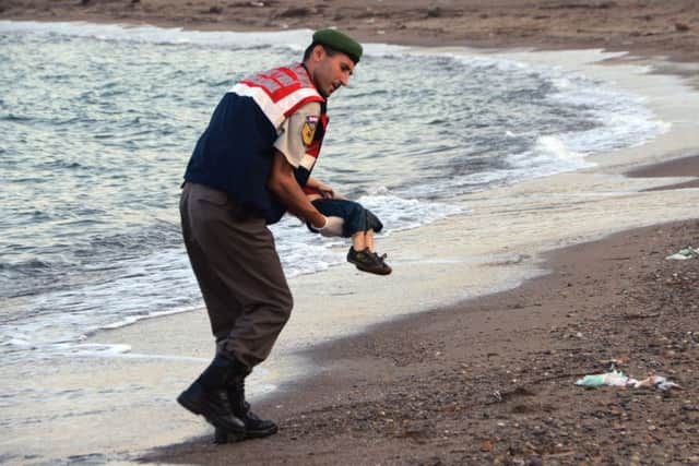 A paramilitary police officer carries the lifeless body of a  migrant child after a number of migrants died when boats carrying them to the Greek island of Kos capsized, near the Turkish resort of Bodrum