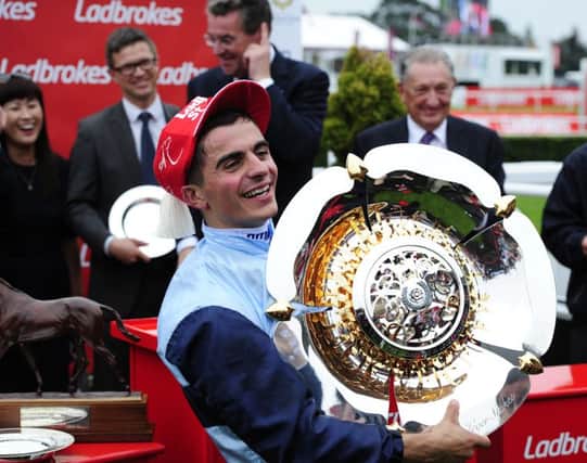 Andrea Atzeni wears the St Leger winning jockey hat watched by Roger Varian the trainer of Kingston Hill in 2014.