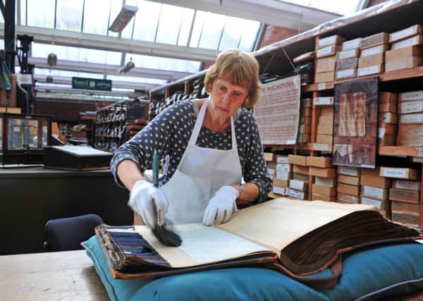 Volunteer Wendy Adams cleans a guard book in the textile archive held at Sunny Bank Mills in Farsley. Picture by Tony Johnson.