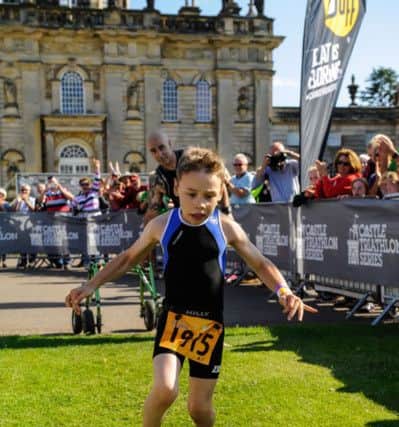 Bailey Matthews  crosses the finish line  to complete his first ever triathlon at Castle Howard