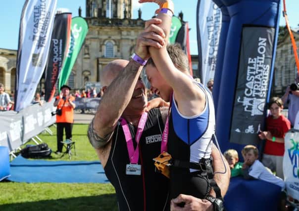 Bailey Matthews  is congratulated by his dad Jonathan  after  crossing  the finish line  to complete his first ever triathlon at Castle Howard