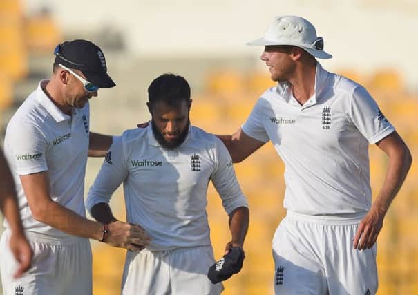 England's James Anderson, left, and Stuart Broad present the ball to Adil Rashid, center, for his five wicket haul during the final day of first test match between Pakistan and England at Zayed Cricket Stadium in Abu Dhabi, United Arab Emirates, Saturday, Oct.17, 2015. (AP Photo/Hafsal Ahmed)
