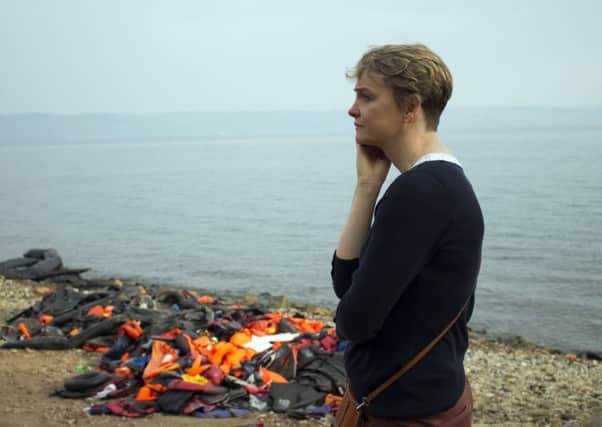 Yvette Cooper MP  stood next to a pile of discarded life jackets on the island of Lesbos.