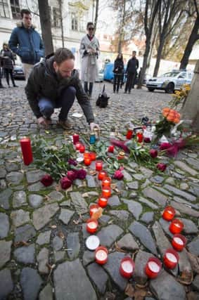 A man lights a candle in front of the French embassy in Prague to mourn for the victims.