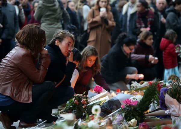 People lay flowers and tributes outside Le Carillon bar, Paris, one of the venues for the attacks in the French capital