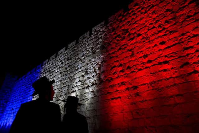 Two Ultra-Orthodox Jews look at Jerusalem's Old City walls illuminated by the colors of the French national flag in solidarity with France