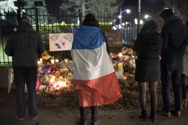 A person wears a French flag at a memorial outside the French Embassy in Ottawa, Ontario, following deadly attacks in Paris on Friday.