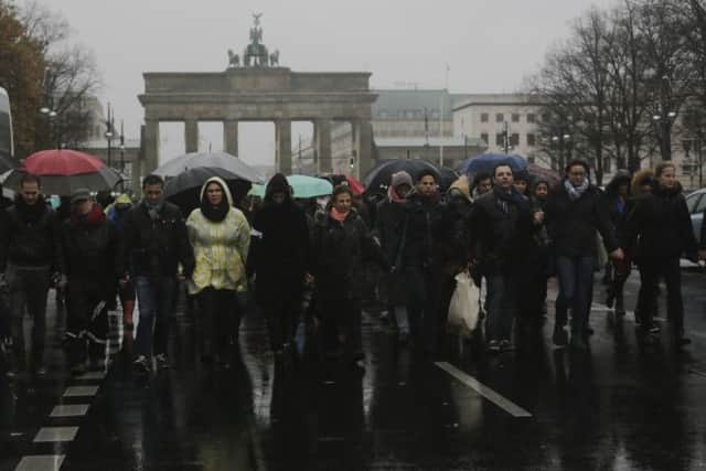 People attend a walk of silence  for the victims killed in the Friday's attacks in Paris, France, in front of the Brandenburg Gate  in Berlin