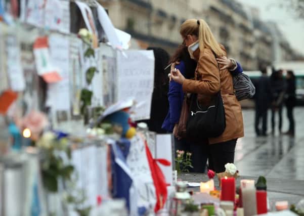 People look at floral tributes and candles left at Place de la Republique in Paris following the terrorist attacks on Friday evening. PIC: PA