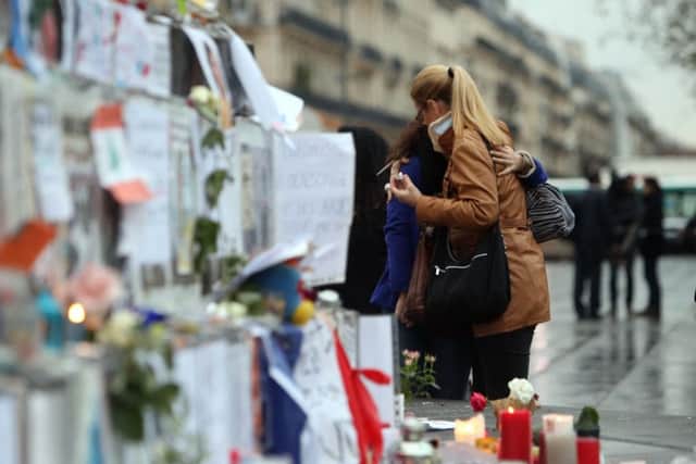 A woman joins crowds looking at floral tributes and candles left at Place de la Republique in Paris following the terrorist attacks on Friday evening.