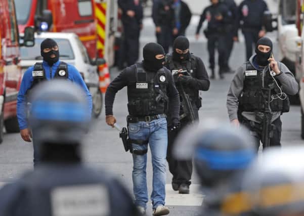 Hooded police officers walk in a street of  Saint-Denis, near Paris.