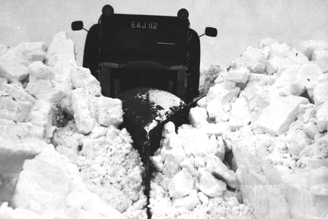 Arctic scene at the Reeth Brough Road in January 1963. A 10 ton snow plough carves its way through drifts which have been cut up into large blocks by workmen. The plough scatters the blocks like childrens bricks.