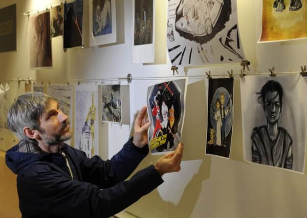 Chris Taylor from Baildon hangs his photo of himself dressed as Darth Vader and work colleagues as other Star Wars characters amongst other artworks inspired by the film francise.   Picture: Bruce Rollinson