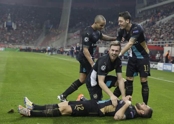Arsenals Olivier Giroud lies prostrate as team-mates Aaron Ramsey, centre, Mesut Ozil, right, and Theo Walcott congratulate him after scoring against Olympiacos (Picture: AP).
