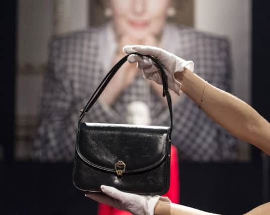 A Christie's staff member holds a classic navy blue leather handbag by Launer, estimated at £2000 to £3000, during a press view of Mrs Thatcher: Property from the Collection of The Right Honourable The Baroness Thatcher of Kesteven Sale, which is due to take place today. (Picture: Lauren Hurley/PA Wire)