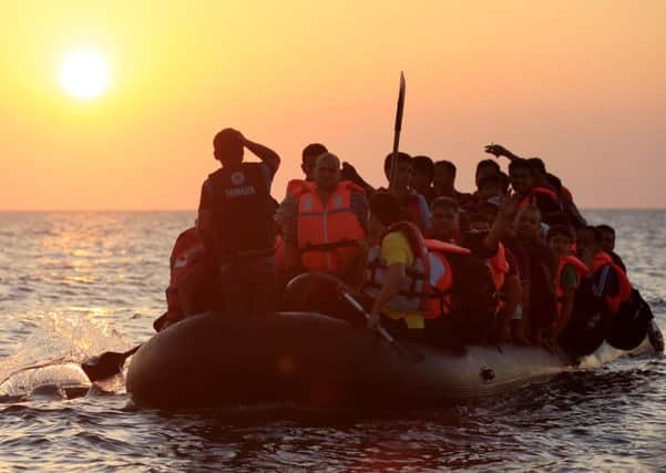Migrants and refugees paddling a rubber dinghy close to the beach at Psalidi near Kos, Greece.