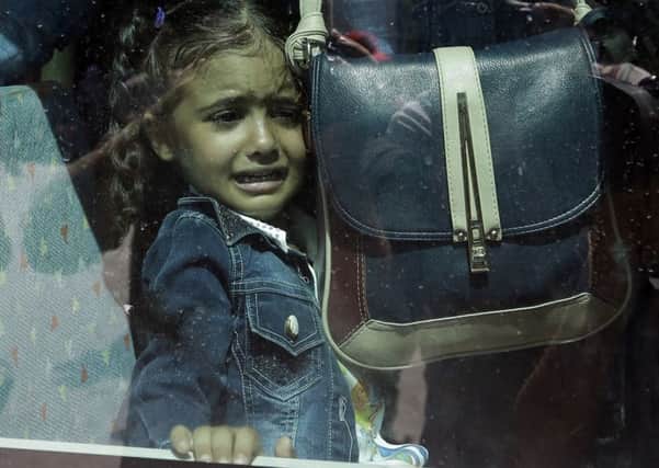 A girl cries as she waits on a bus which will transport her family to the metro station, after their arrival from the northeastern Greek island of Lesbos to the Athens' port of Piraeus.