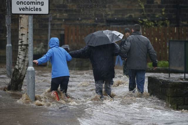 People wade through flood waters at Mytholmroyd in Calderdale, West Yorkshire.