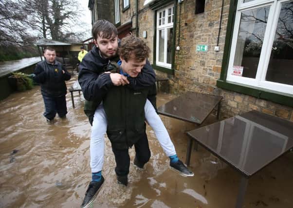 A man gives his friend a piggy back to escape rising flood water. The village of Ribchester on the River Ribble, Lancashire has burst its banks in the early hours of this morning Saturday 26 December. A Severe flood warning has been issued with a danger to life. Heavy rain fell over Christmas night and forecasters have warned it will continue in Lancashire for most of the day. Rivers in the are are expected to peak around mid-day.