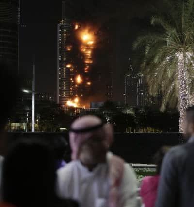 Smoke and flames pouring from a residential building, which also contains the Address Downtown Hotel, in Dubai, United Arab Emirates.  (AP Photo/Sunday Alamba)