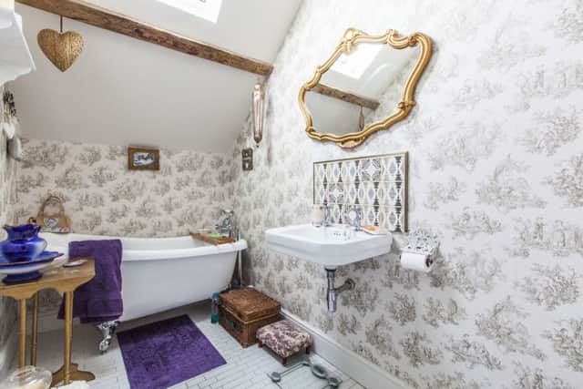 The bathroom was given  a glamorous makeover with new tiles, wallpaper, mirror and a chandelier