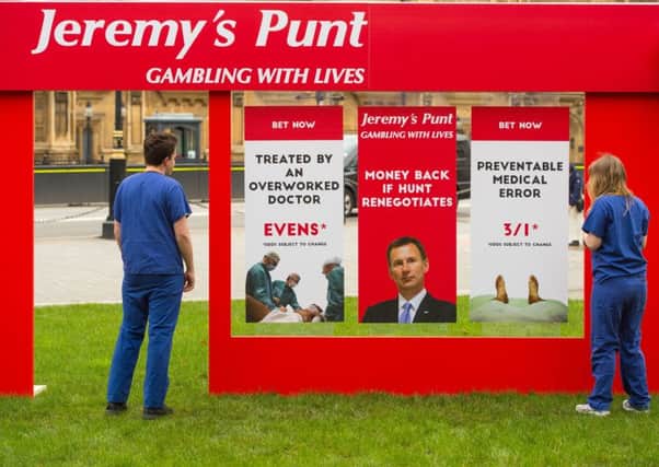 Campaigners dressed as junior doctors with a fake betting shop storefront outside the Houses of Parliament, as campaign groups call attention to Health Secretary Jeremy Hunt's plan to reform junior doctor's contracts