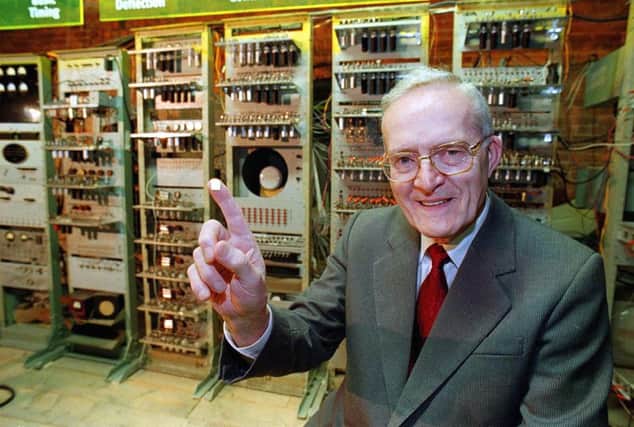 Professor Tom Kilburn with tiny modern day computer 'chip' on his finger, whilst in the background is "Baby" - the worlds first computer which Prof Kilburn helped build in 1948. (Picture: Jeff Morris/PA)