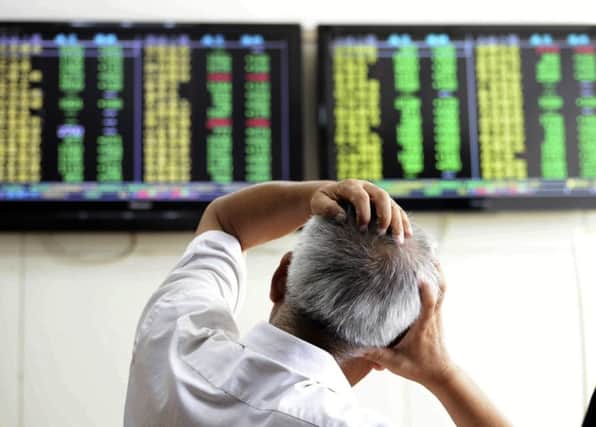 A Chinese stock investor reacts near a display for stock prices at a brokerage house in Qingdao in eastern China's Shandong province Tuesday, Aug. 25, 2015  (Chinatopix via AP)