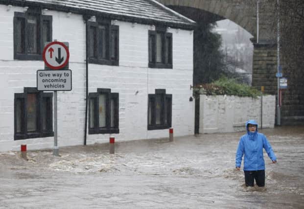 People wade through flood waters at Mytholmroyd in Calderdale, on Boxing Day. Picture: Peter Byrne/PA Wire