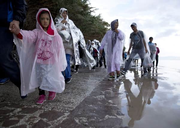 Afghan migrants walk on a street in the rain, after they arrived with from Turkey to the shores of the Greek island of Lesbos.