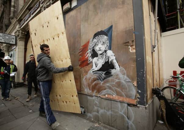 Workmen begin to cover up a new artwork by Banksy, depicting the girl from Les MisÃ©rables affected by tear gas, opposite the French embassy in Knightsbridge, London.