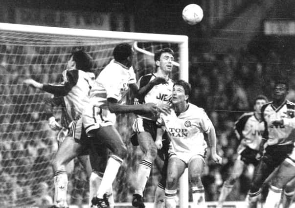 Leeds defender Chris Whyte leaps for this cross surrounded by the Arsenal defence while team-mate John Pearson looks on.