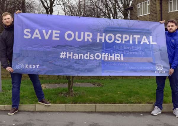 Elliott  Hinchliffe (Left) and Karl Deitch from 'Hands Off HRI' with a banner  at Huddersfield Royal Infirmary.