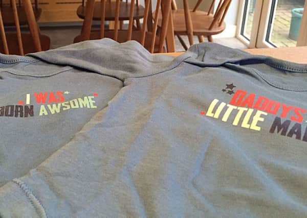 Two baby suits from Tesco, one carrying the slogan "I was born awsome" - missing out the first E in 'awesome' (left) and the other missing a possessive apostrophe as it reads "Daddys little man" (right), resulting in the supermarket chain promising to brush up on its spelling and grammar.