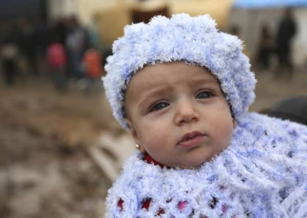 A Syrian baby is carried as the family arrives at the Bab al-Salam border crossing with Turkey, in Syria.