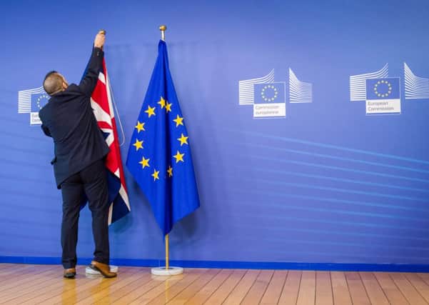 An EU official hangs the Union Jack next to the European Union flag at the VIP entrance at the European Commission headquarters in Brussels.