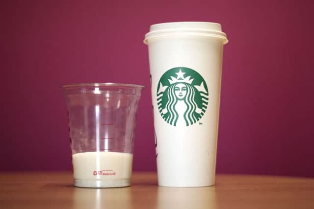 A cup of Starbucks' venti Grape with Chai, Orange and Cinnamon Hot Mulled Fruit which had a total of 25 teaspoons of sugar per serving next to with a cup containing 25 teaspoons of sugar